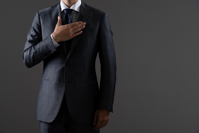 胸に手を当てるスーツ男性
